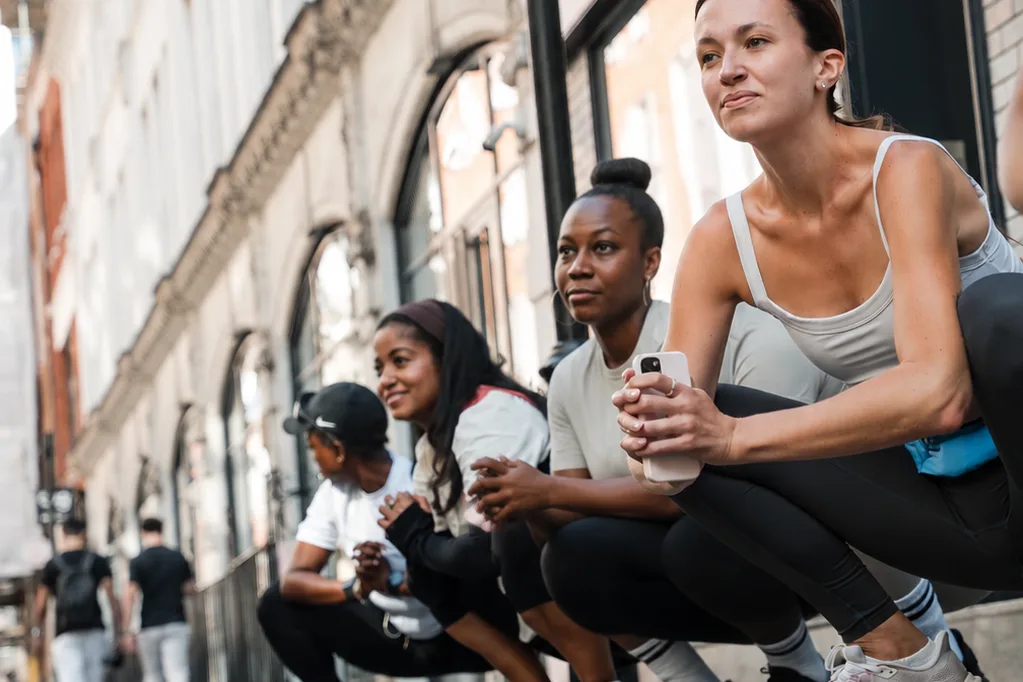 Four of the crew crouched along the kerb outside a London shopfront before a run, water bottles in hand.